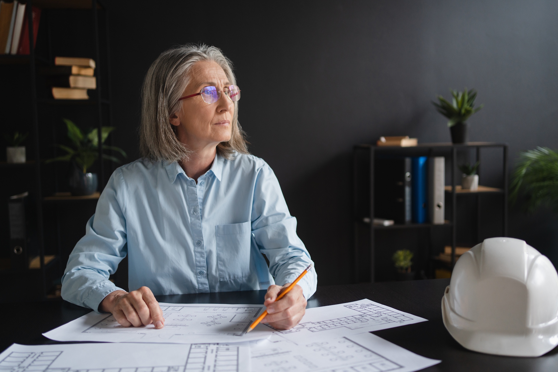 Senior engineer reviewing rolled construction drawings on site